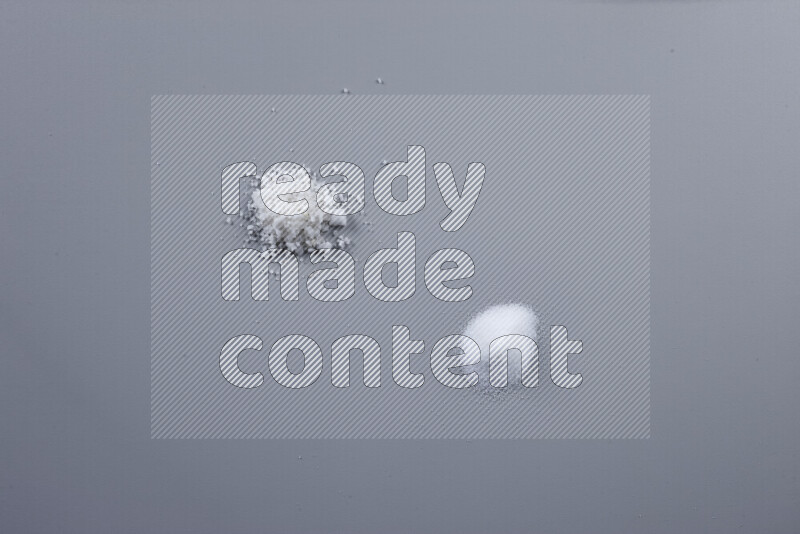 Bunches of table salt, coarse sea salt, fine himalayan salt and coarse himalayan salt on grey background