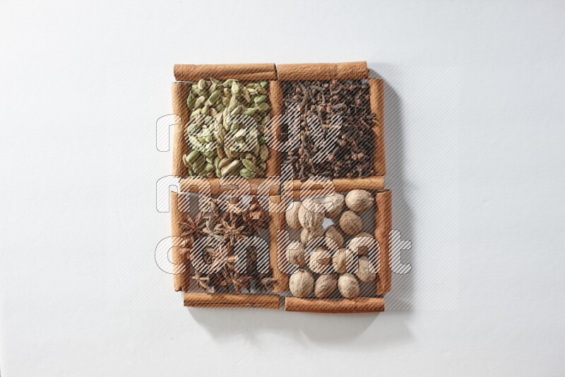 4 squares of cinnamon sticks full of cardamom, star anise, cloves and nutmeg on white flooring