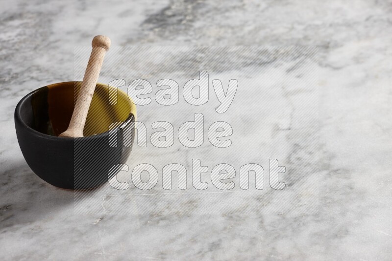 Multicolored pottery bowl with wooden honey dipper in it on grey marble background