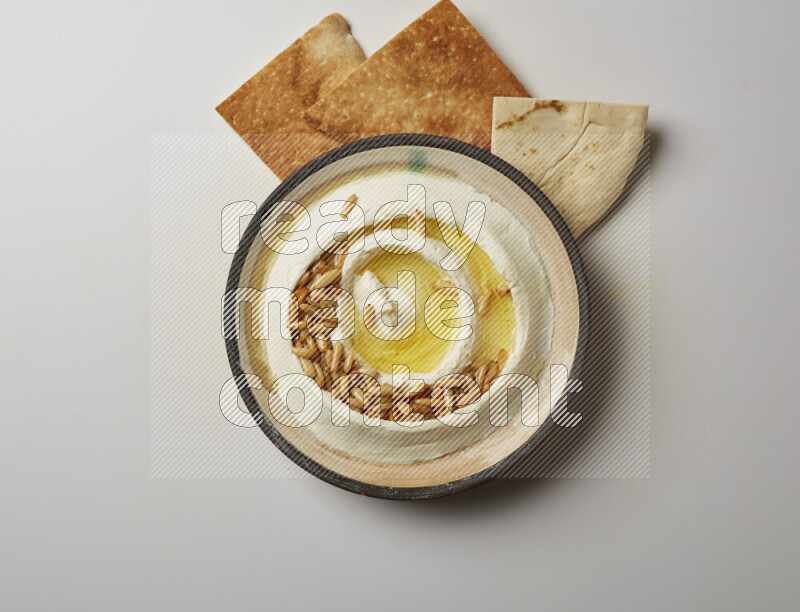 Lebnah garnished with pine nuts in a pottery plate on a white background