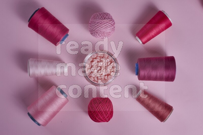 A pink collection of sewing and tailoring tools arranged on a pink background