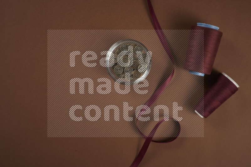 A red collection of sewing and tailoring tools arranged on a brown background