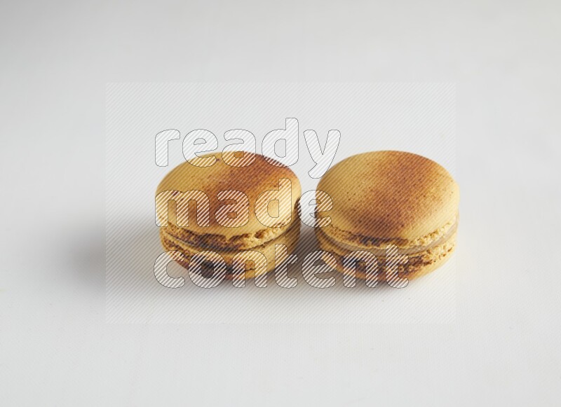 45º Shot of two Yellow Crème Brulée macarons on white background