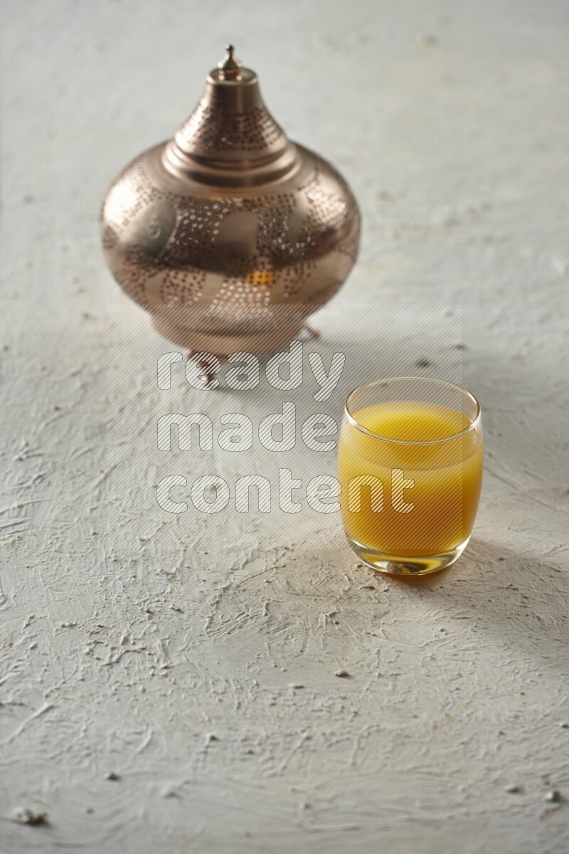A golden lantern with different drinks, dates, nuts, prayer beads and quran on textured white background