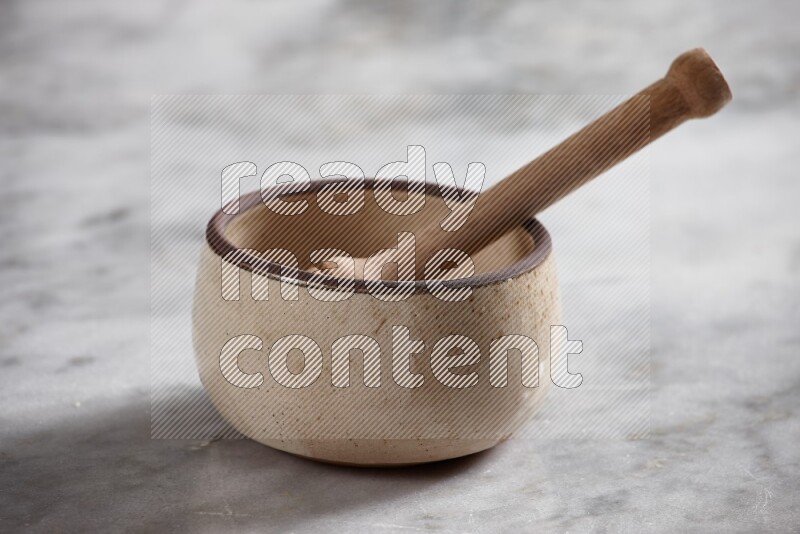 Beige Pottery Oven Bowl with wooden honey handle on the side with grey marble flooring, 15 degree angle