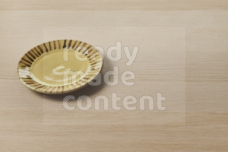 A multicolored pottery plate on light wooden background