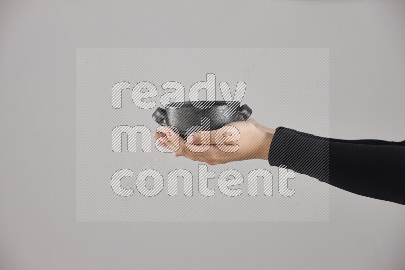 A woman in black abaya holding different pottery essentials in different positions