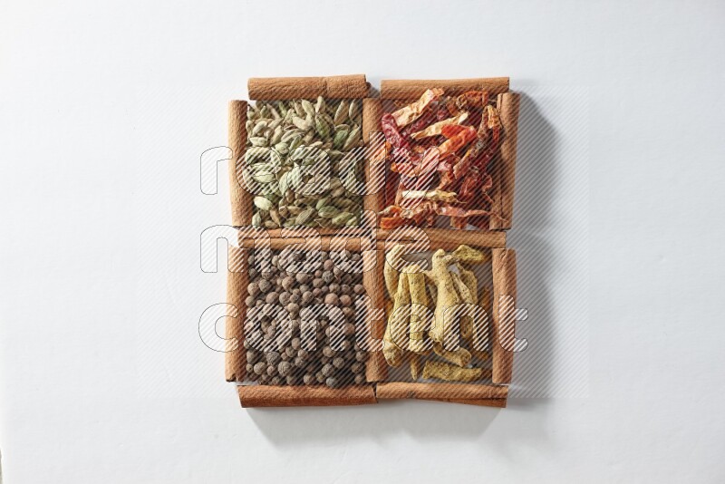 4 squares of cinnamon sticks full of dried red chilis, cardamom, turmeric fingers and allspice on white flooring