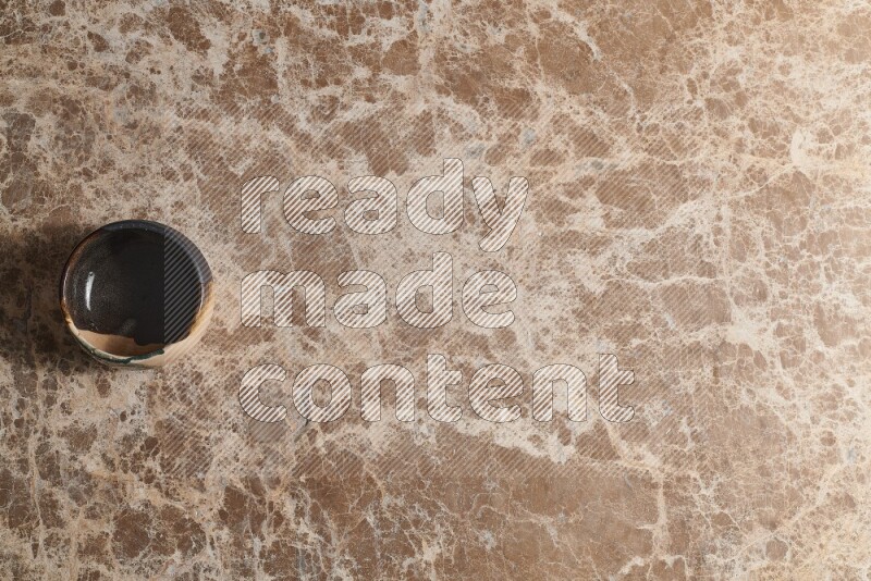 A multicolored pottery bowl on beige marble background