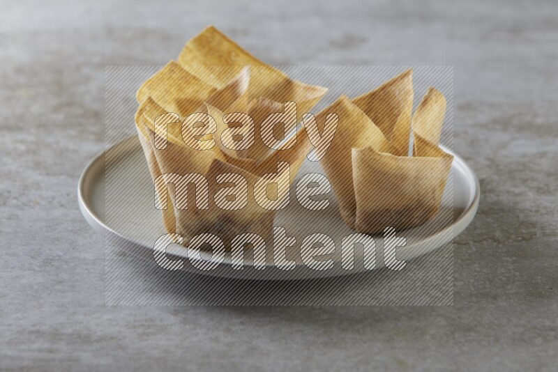 wonton cups with soy sauce ramkin on grey ceramic plate on grey textured counter top
