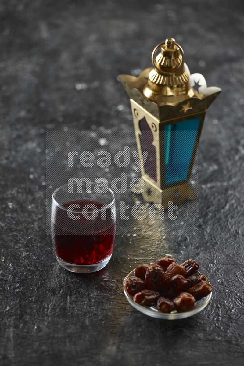A golden lantern with different drinks, dates, nuts, prayer beads and quran on textured black background