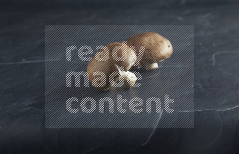 45 degre cremini  mushrooms on a textured black slate background