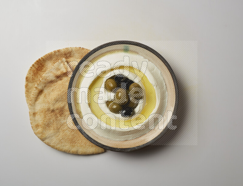 Lebnah garnished with whole black olives in a pottery plate on a white background