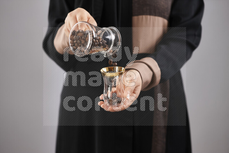 Woman in abaya holding different kinds of coffee beans in different positions