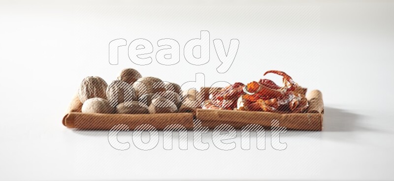 2 squares of cinnamon sticks full of dried red chilis and nutmegs on white flooring