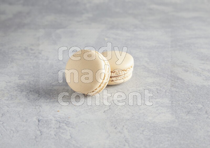 45º Shot of two white marbleCaramel fleur de sel macarons  on white  marble background