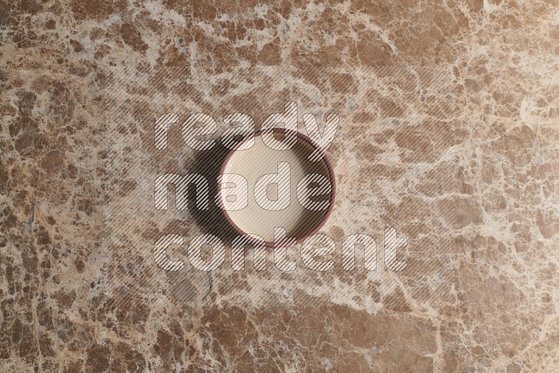 A beige pottery oven plate on beige marble background