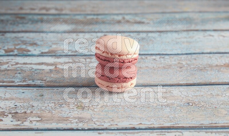 45º Shot of two Pink Litchi Raspberry macarons on light blue wooden background