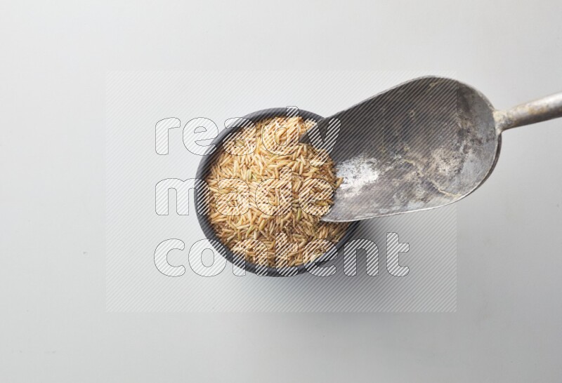 Top-view shot of long grain brown rice in a container on white background
