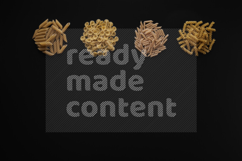 Different pasta types in 4 bunches on black background