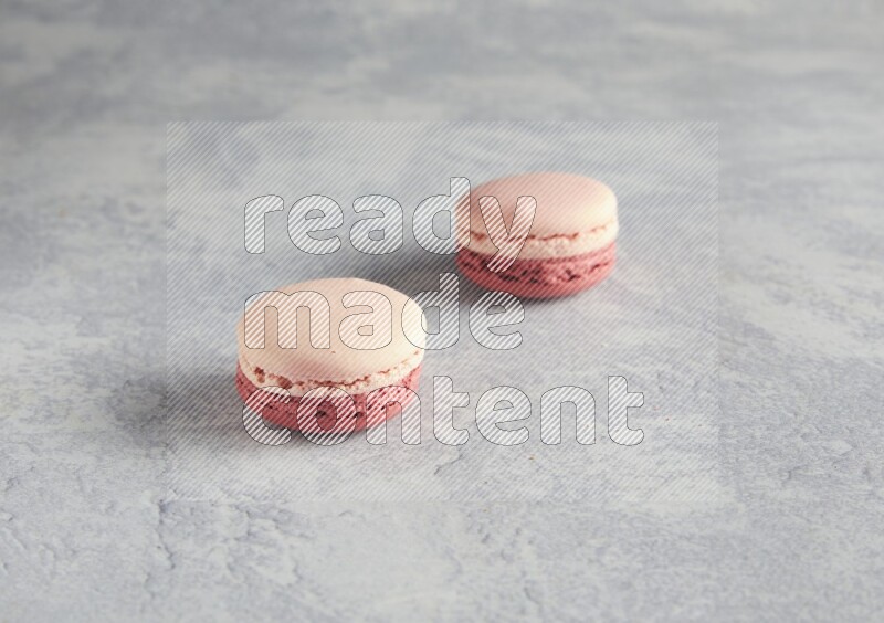 45º Shot of two Pink Litchi Raspberry macarons  on white  marble background