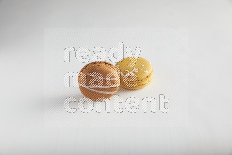 45º Shot of of two assorted Brown Irish Cream, and Yellow Piña Colada macarons on white background