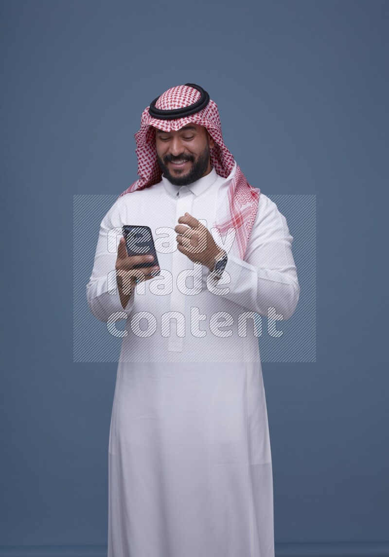 A man Texting on Blue Background wearing Saudi Thob and Shomag