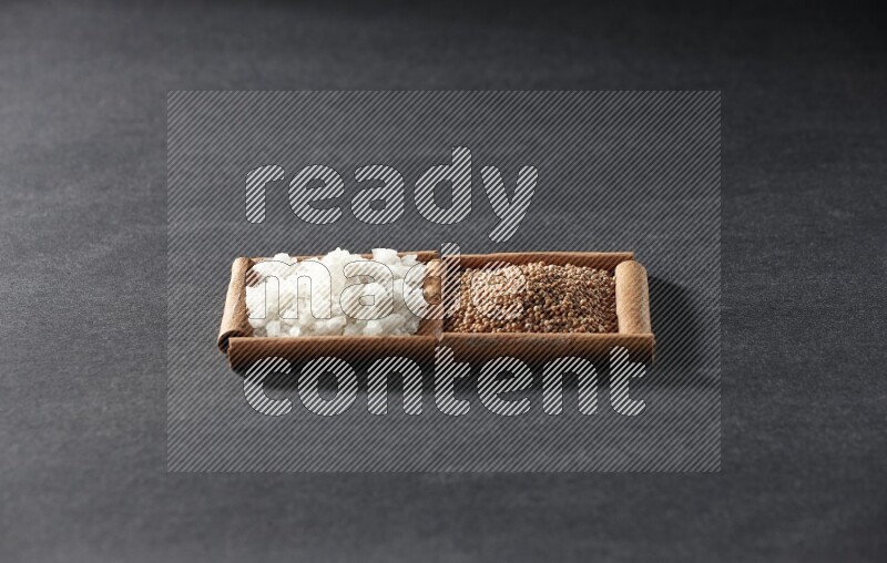 2 squares of cinnamon sticks full of mustard seeds and white salt on black flooring