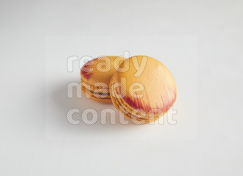 45º Shot of two orange Exotic macarons on white background