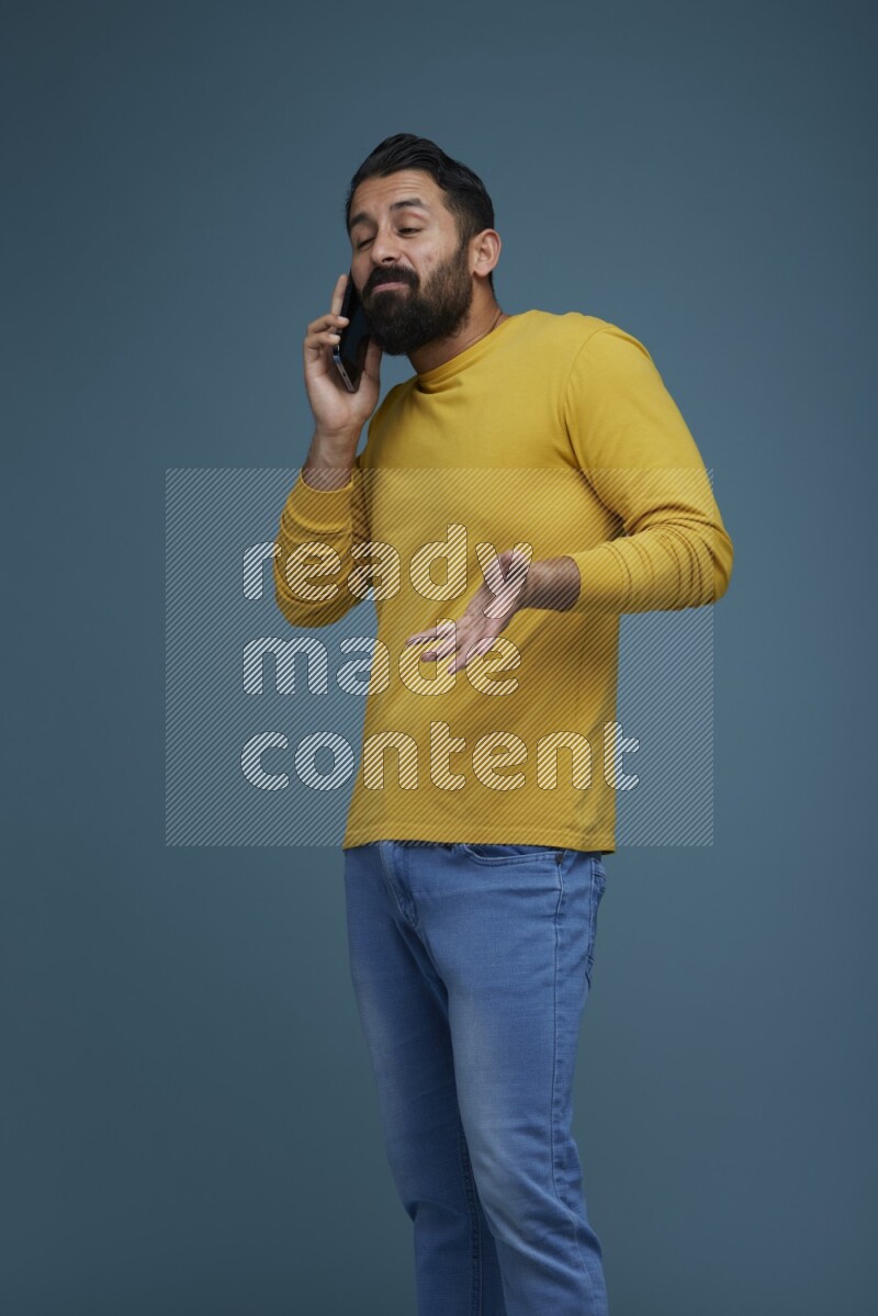 A man having a calling in a blue background wearing a yellow shirt