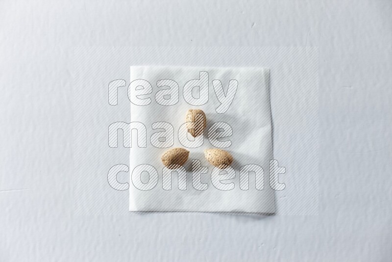 3 almonds on a piece of paper on a white background in different angles