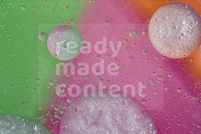 Close-ups of abstract oil bubbles on water surface in shades of orange, green and pink