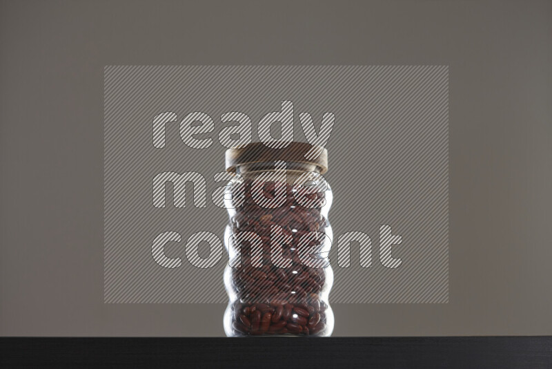 Red kidney beans in a glass jar on black background