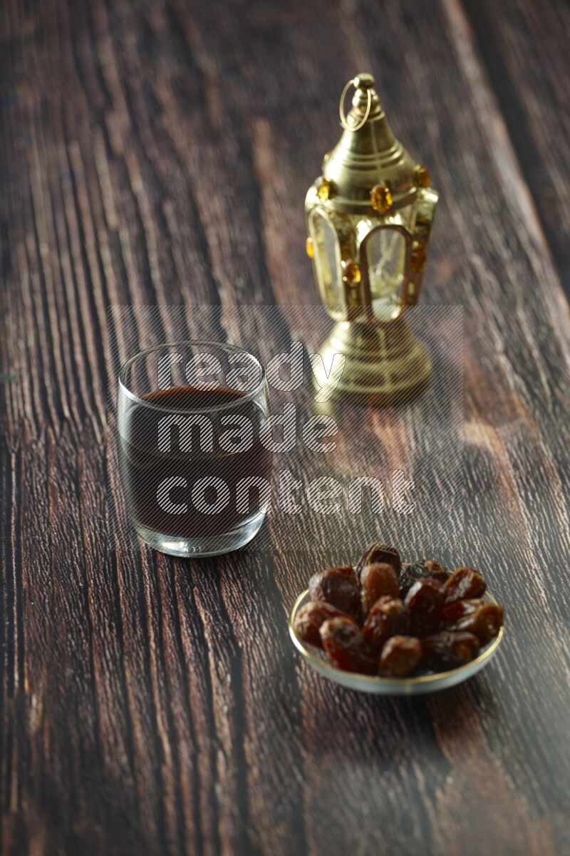 A golden lantern with different drinks, dates, nuts, prayer beads and quran on brown wooden background