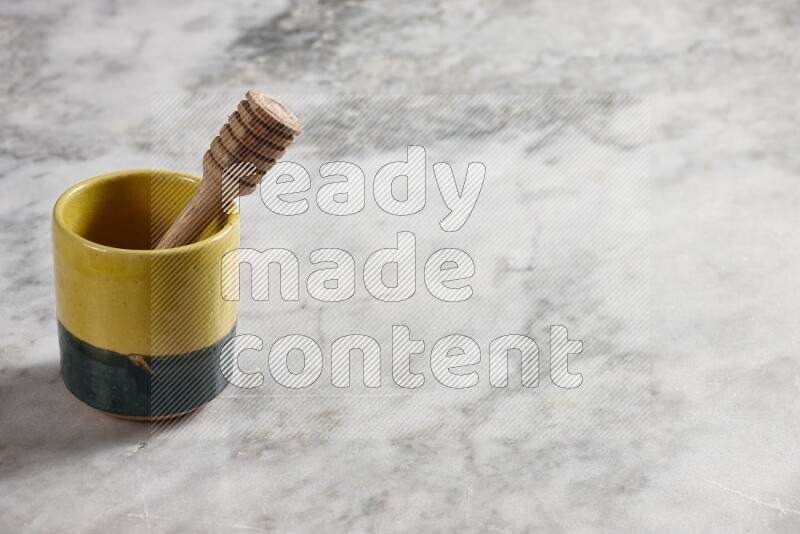 Multicolored pottery cup with wooden honey dipper in it on grey marble background