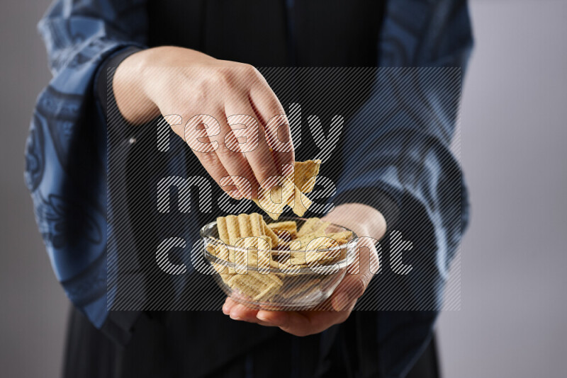 Woman in abaya holding different kinds of snacks in different positions