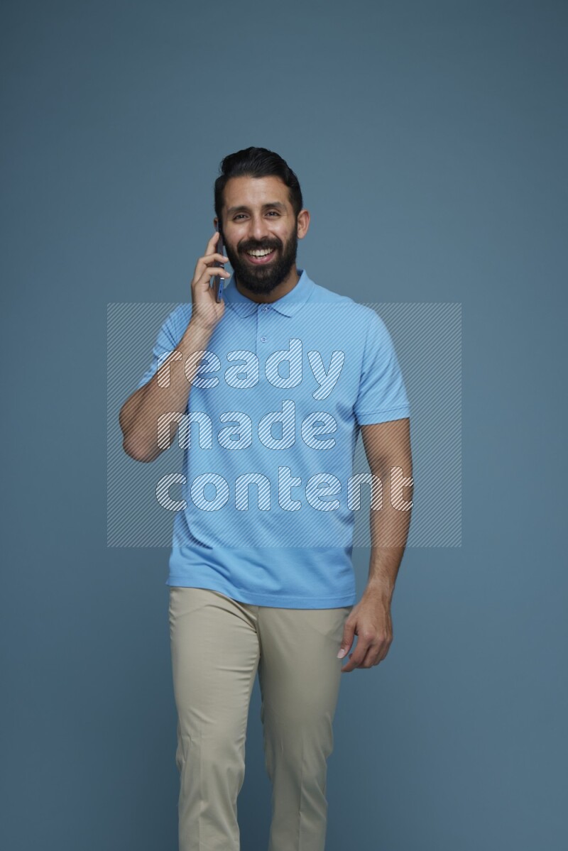 A man having a Call in a blue background wearing a Blue shirt