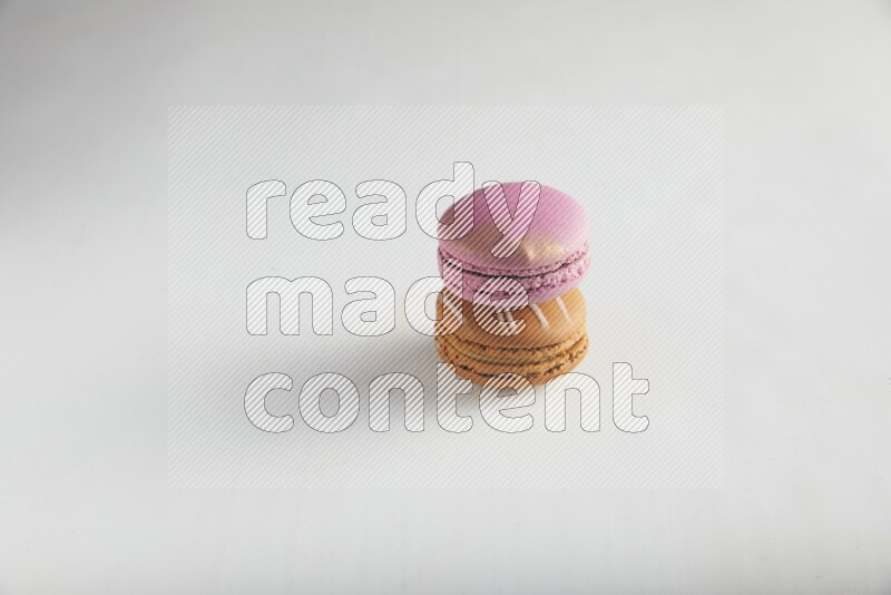 45º Shot of of two assorted Brown Irish Cream, and Purple Strawberry macarons on white background