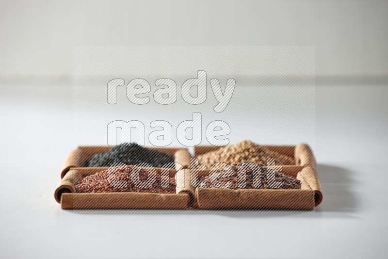 4 squares of cinnamon sticks full of black seeds, mustard seeds, flaxseeds and garden cress on white flooring