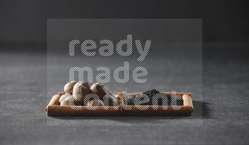 مربعان من أعواد القرفة ممتلئان بحبة البركة السوداء وجوزة الطيب علي خلفية سوداء