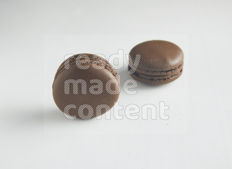 45º Shot of two Brown Dark Chocolate macarons on white background