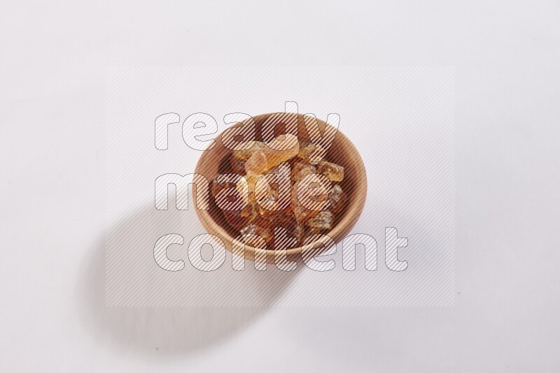 A wooden bowl full of gum arabic on a white flooring