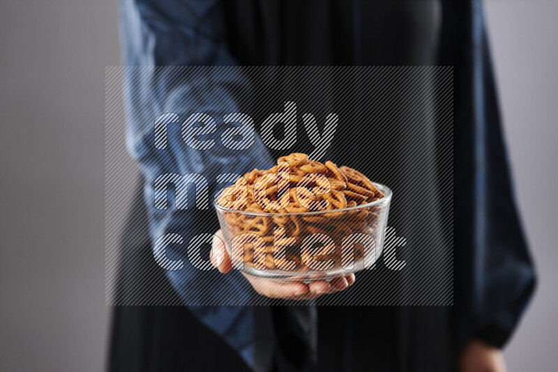 Woman in abaya holding different kinds of snacks in different positions