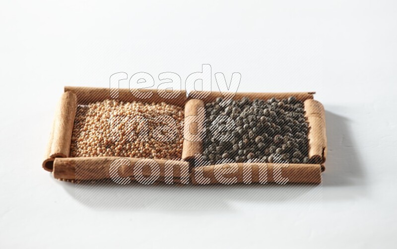 2 squares of cinnamon sticks full of mustard seeds and black peppers on white flooring