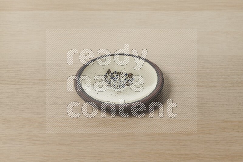 A decorative pottery plate on light wooden background