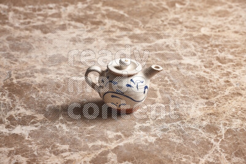 A pottery teapot on beige marble background