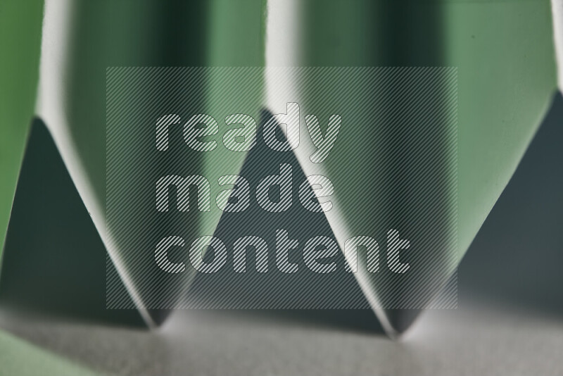 A close-up abstract image showing sharp geometric paper folds in white and green gradients