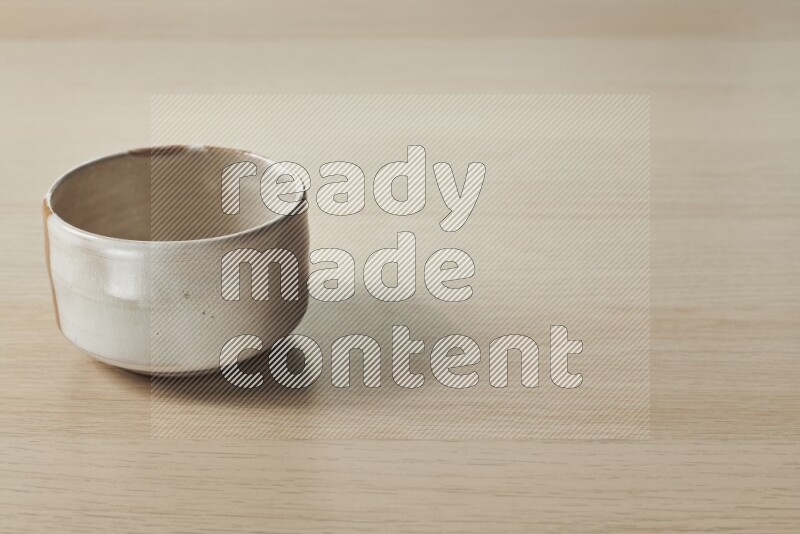 A beige pottery bowl on light wooden background