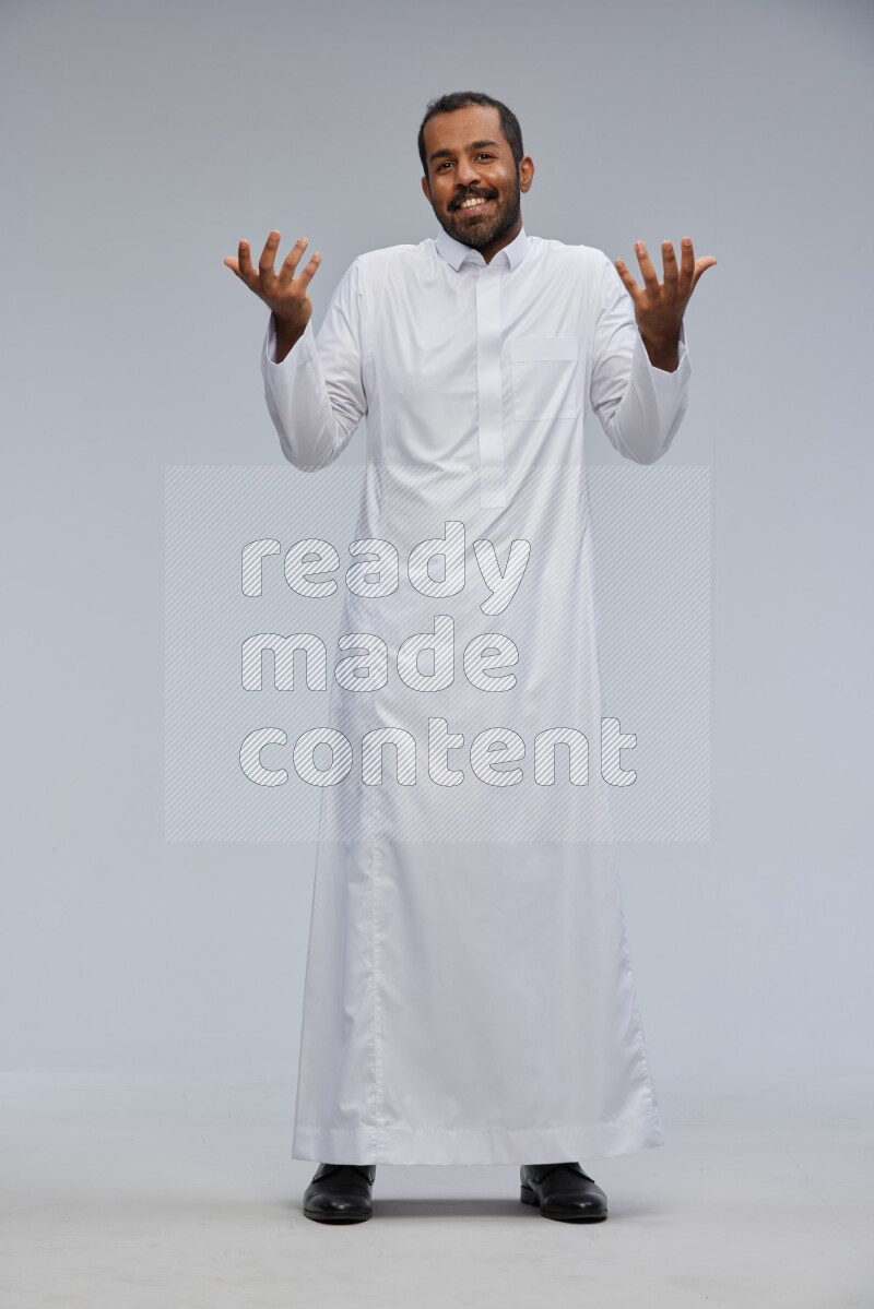 Saudi man Wearing Thob standing interacting with the camera on Gray background