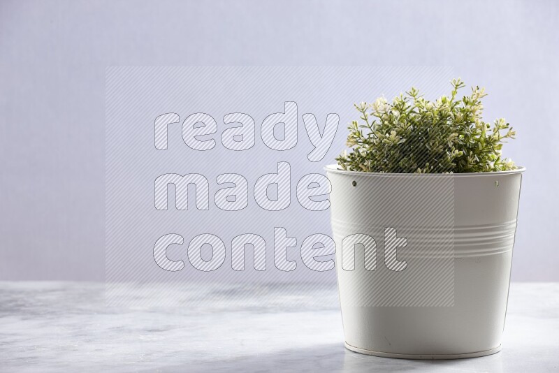 Artificial plant in white pot on grey marble background